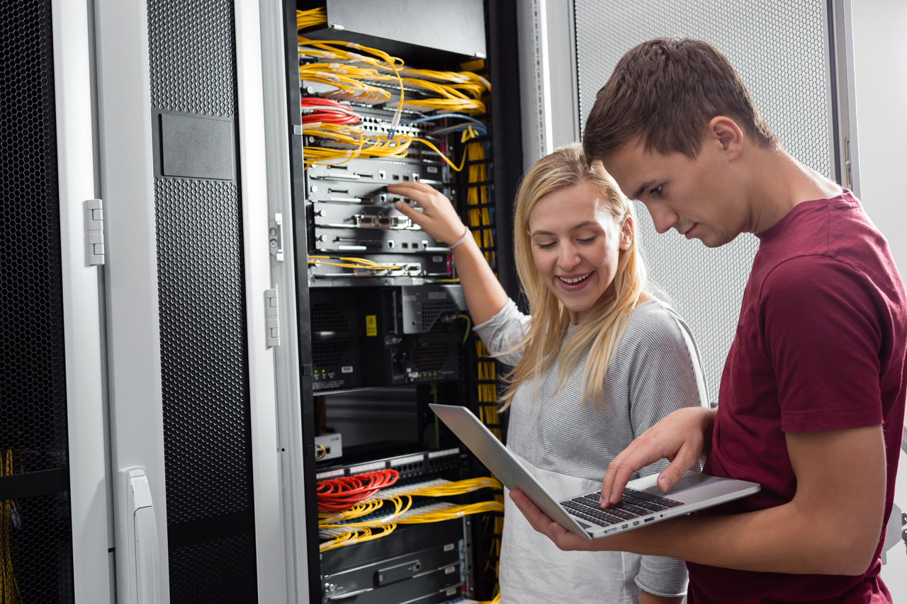 Eine IT-Expertin und ein IT-Experte reparieren den Server 